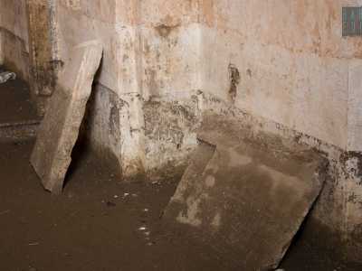 Esploriamo il vano completamente spoglio, camminando su una superficie resa scivolosa dalla fanghiglia. La pavimentazione originaria � stata infatti trafugata, al pari dell'acquasantiera un tempo posizionata sulla sinistra dell'accesso. Addossate sui muri notiamo qua e l� delle lastre di pietra scampate alle attenzioni dei ladri
